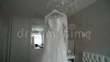 豪华婚纱挂在卧室里。 令人惊叹的新娘`蕾丝礼服的剪影。 早上的准备，开始